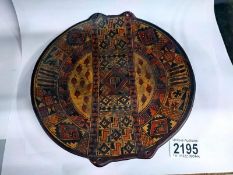 A shallow painted pottery plate with tribal design. 21cm diameter. 21.5cm top to bottom.