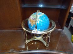A stone globe on brass effect stand. 14cm diameter.