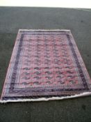 A pink patterned Persian style rug. Length 240cm x 170cm. COLLECT ONLY.