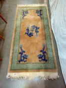 A beige and green rug with Blue dragon motifs. 172 cm x 78cm