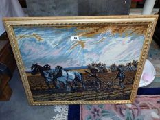 A framed and glazed cross-stitch of an agricultural scene. A pair of heavy horses ploughing a