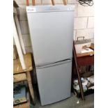 A grey Candy fridge freezer, clean with instructions.