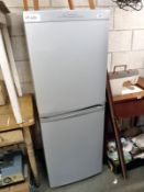 A grey Candy fridge freezer, clean with instructions.