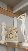 A classical style mantel clock and two nude figures.