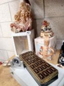 A porcelain doll, musical merry go round, vintage chocolate tin and a travel alarm