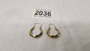A pair of 9ct gold tested hoop earrings in a textured design.