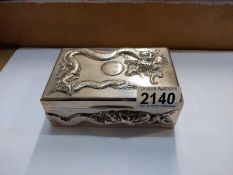 A silver cigarette box with embossed dragons.