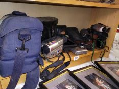 A shelf of cameras binoculars, phones etc.