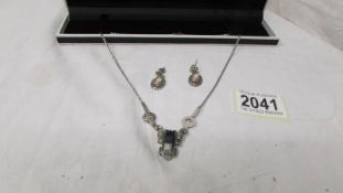 An deco style pendant in silver marcasite and a pair of silver ear pendants with female profiles.