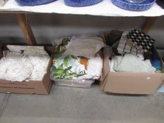 Three boxes of assorted household linen including sheets, cushions, table cloths towels etc.,