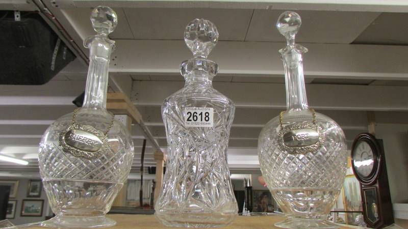 A pair of cut glass decanters with labels and another cut glass decanter.