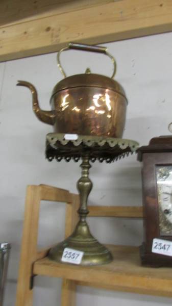 A copper kettle and a brass trivet.