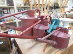 Five long spout metal watering cans being 4 red stamped 'Haws' (one base rusted through)