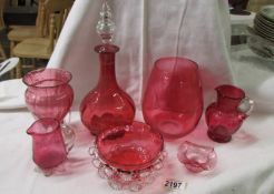 Seven pieces of cranberry glass including decanter, jugs, vase etc.,