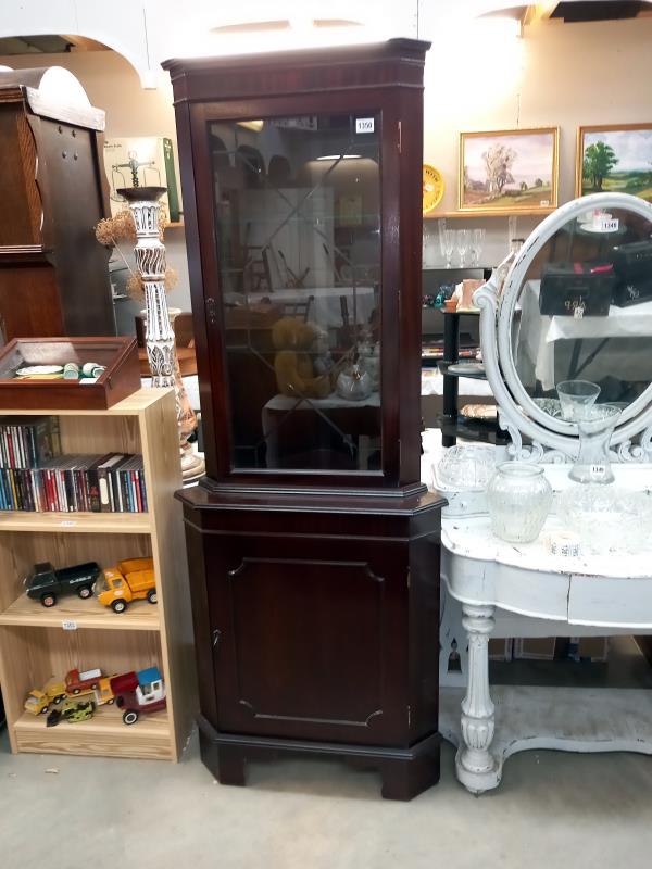 A dark wood stained corner cupboard with cut glass door panel 70 cm x 49cm x height 184 cm.