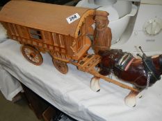 A ceramic horse with wooden cart and a carved wood figure.