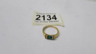 An 18ct gold ring set four diamonds and a green stone, size K half, 3.7 grams.