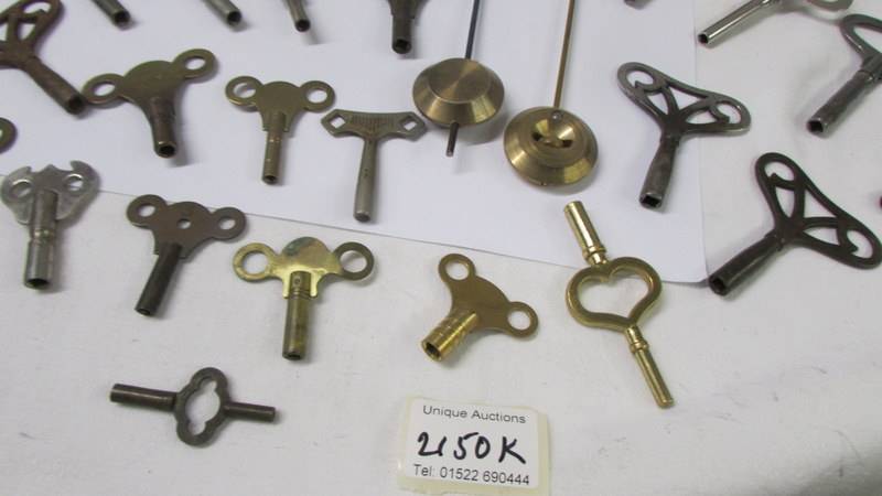 In excess of 28 old clock keys, pendulums and bells. - Image 4 of 4