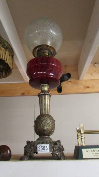 A Victorian oil lamp with ornate brass base, ruby glass font and acid etched shade. COLLECT ONLY.