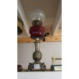 A Victorian oil lamp with ornate brass base, ruby glass font and acid etched shade. COLLECT ONLY.