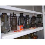 A shelf of vintage Hurricane/Tilley lamps