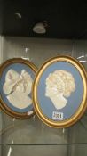 Two oval ceramic wall plaques of female heads.