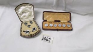 A cased set of six mother of pearl buttons and a cases set of cufflinks with matching tie pins.