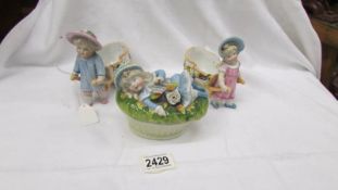 A pair of Victorian porcelain girl figures pulling barrows and a butter dish with reclining figure.