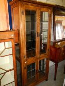 A modern oak cottage style display cabinet with leaded glass door panels (one needs re-fixing),