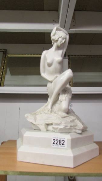 A marble effect semi nude figure on a two tier oxagonal base.
