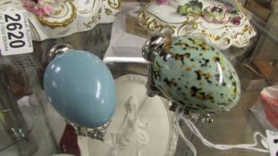 Two porcelain scent bottles in the shape of eggs on stands.