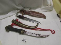 A curved knife in sheath and a hunting knife in leather sheath.