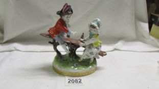 A continental porcelain figure group of a boy and girl on a seesaw.