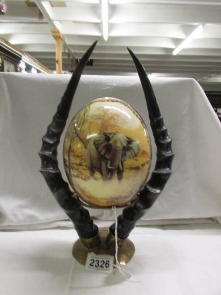 A decorated ostrich egg depicting elephants and other wild animals.