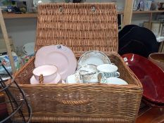 A wicker hamper basket with mixed part tea sets.