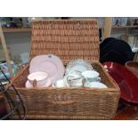 A wicker hamper basket with mixed part tea sets.