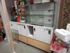 A pair of commercial display cabinets, top half glass with lights and bottom half wood storage