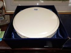A white circular porcelain cake stand with pattern detail.