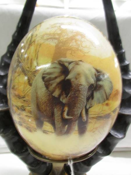 A decorated ostrich egg depicting elephants and other wild animals. - Image 2 of 5