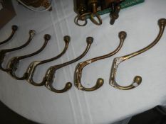 Seven old brass coat hooks.