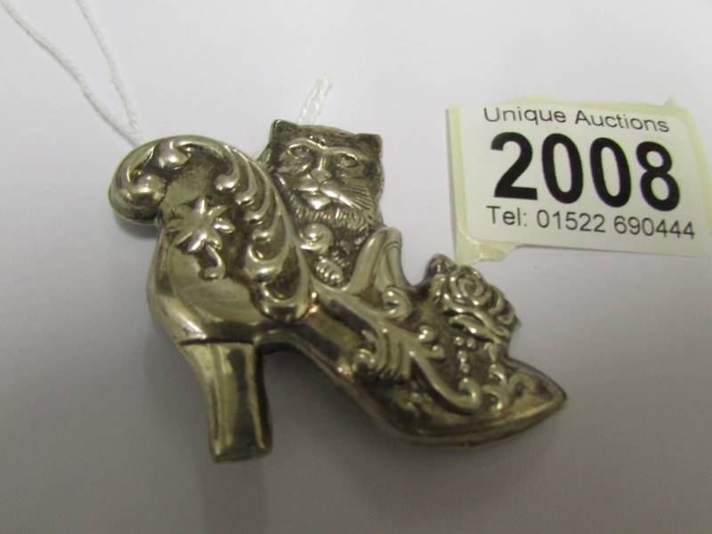 A silver cat in a shoe brooch.