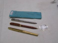 A silver Tiffany pen, a Parker pen and an Yves Saint Laurent pen.