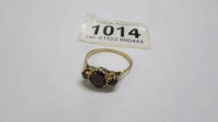 A 9ct gold three stone garnet ring, size T. 2 grams.