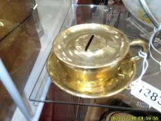A 1920's novelty brass tea cup and saucer money box, Rd. No. 685799.
