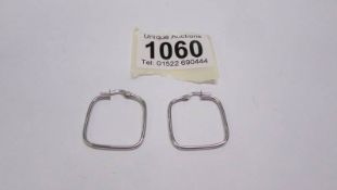 A pair of silver earrings.