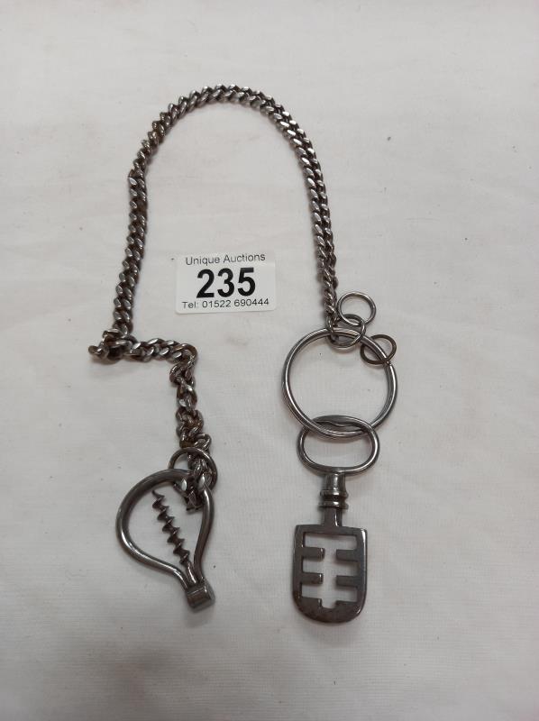 A Victorian metal chain with an antique metal key and an antique metal bottle opener