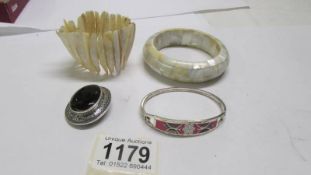 Two mother of pearl bracelets, a silver bangle and a silver mounted brooch.