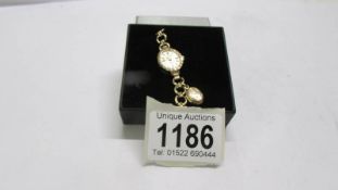 A 9ct gold ladies watch with 9ct gold bracelet and attached opening locket, total weight 11 grams.