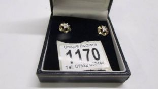 A pair of diamond set ear studs in a flower design gold, set seven diamonds to each stud.