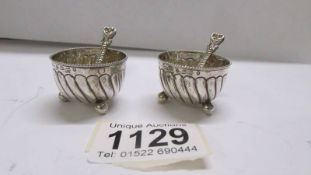 A pair of silver salts with spoons.